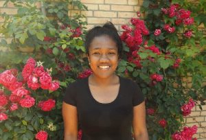 Portrait lächelnde junge Frau aus Madagaskar vor Rosenbusch