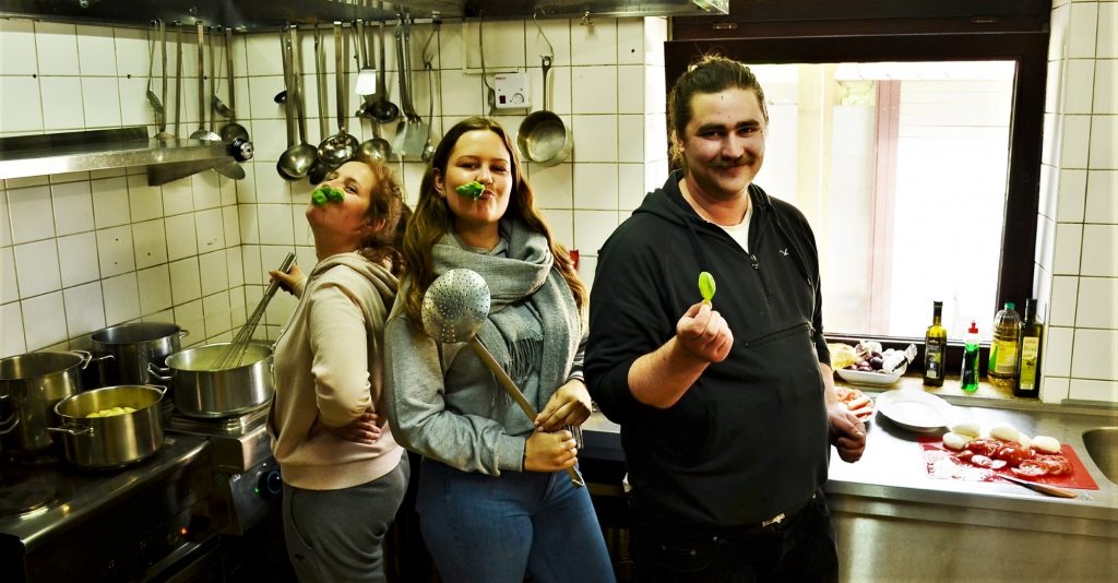 Drei junge Freiwillige bereiten posieren beim Kochen in einer Seminarküche für ein Foto
