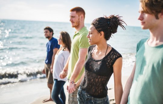 Jugendliche am Strand, die eine Menschenkette bilden