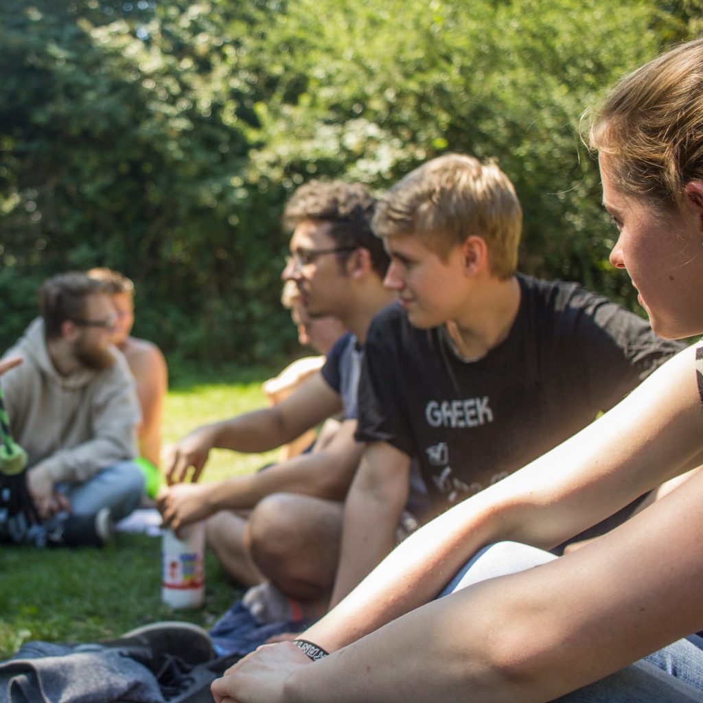 Gruppe Jugendlicher sitzt auf Wiese im Park