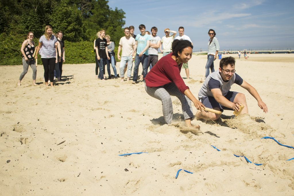 Diverse Gruppe Jugendlicher spielt Team Building Spiele am Strand