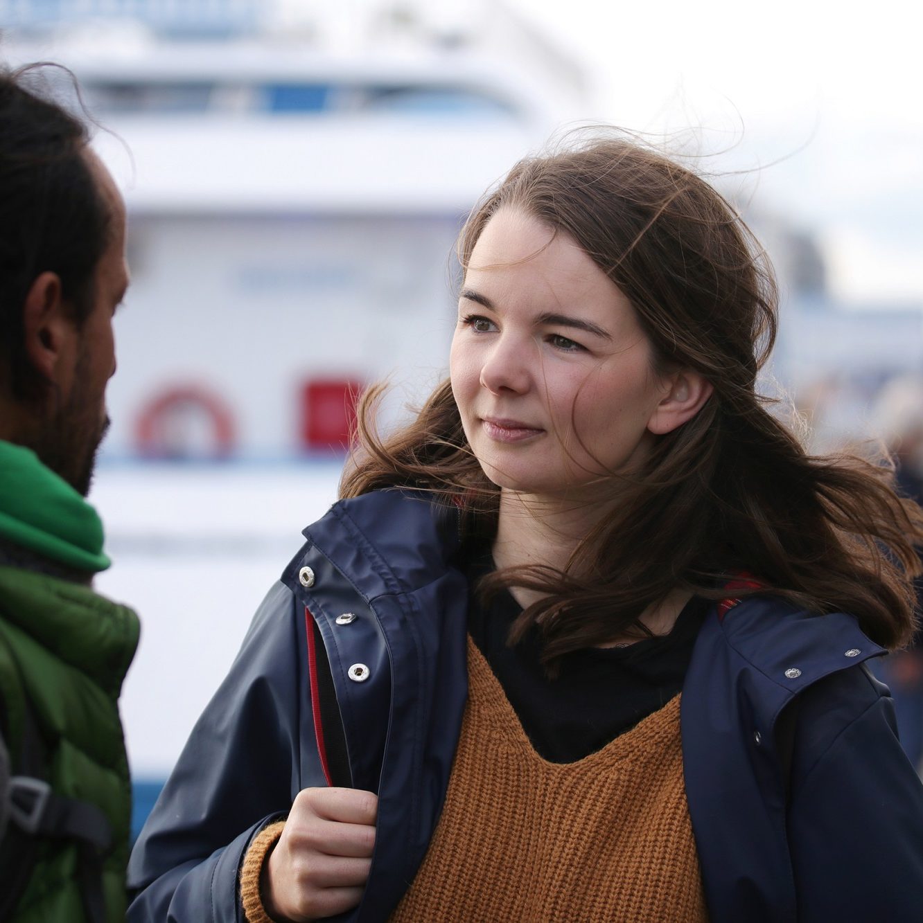 junge Frau mit Rucksack in einem Hafen im Gespräch mit einem jungen Mann